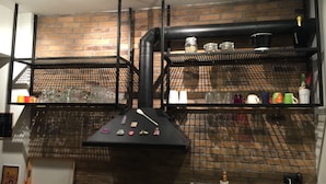 A kitchen with brick walls, black metal shelving, and various kitchen items. - Bright Cozy vintage apartment (Athina)