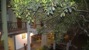 An indoor courtyard with a dining area, a water feature, and a balcony with railings. - Royal Tusker Udawalawa (Udawalawa)
