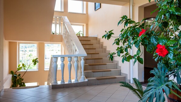 A staircase with white balusters, beige steps, and a view of the outdoors through windows. - Hotel-Restaurant Dumbrava Rupea (Rupea)
