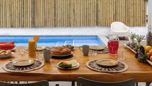 Mesa lista para el desayuno con vista a una piscina.