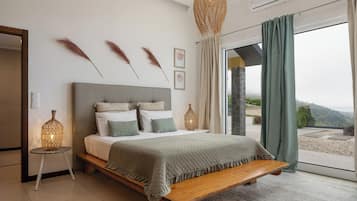 A bedroom with a large bed, bedside lamps, a bench, and a view through a glass door.