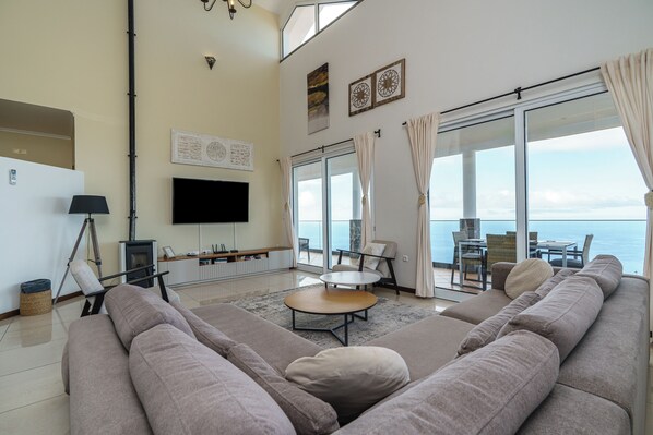 A modern living room with a large sofa, a coffee table, a flat-screen TV, and a fireplace.