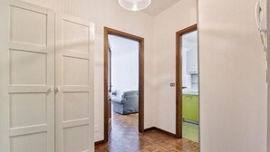 A hallway with a wooden floor, white walls, and a door leading to a room with a green countertop.