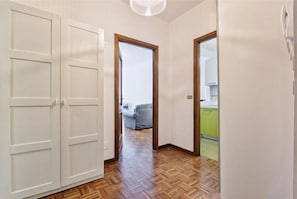 A hallway with a wooden floor, white walls, and a door leading to a room with a green countertop.
