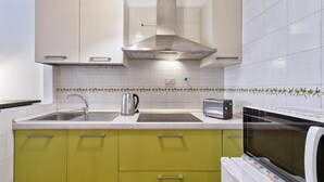A kitchen with a stainless steel range hood, a kettle, a toaster, and a microwave.
