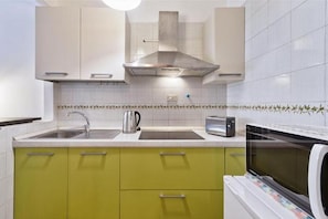 A kitchen with a stainless steel range hood, a kettle, a toaster, and a microwave.