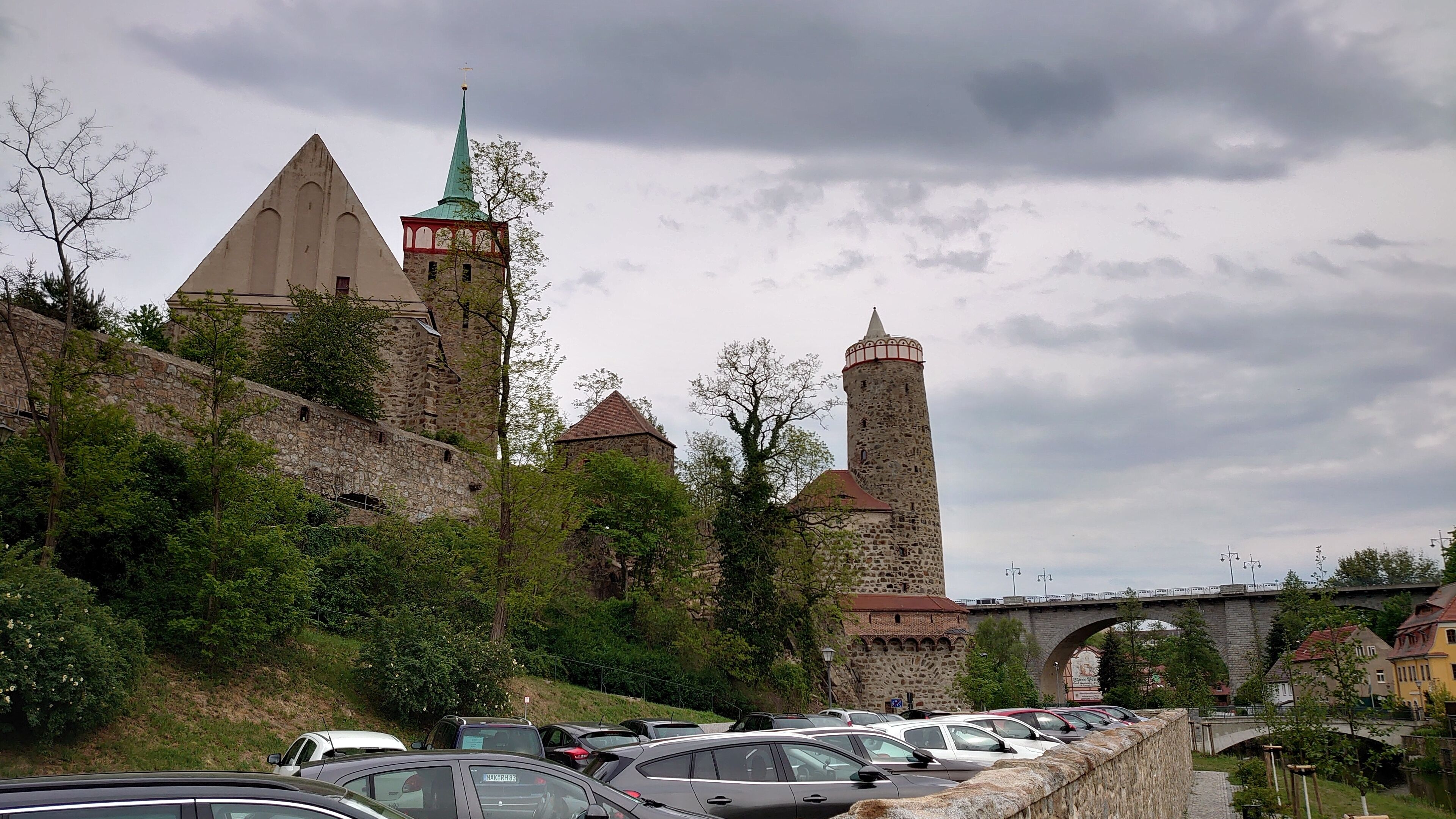 A historic castle with multiple towers, a stone wall, and a bridge.