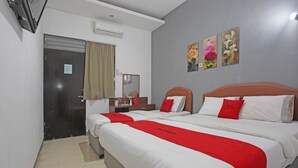 Une chambre d’hôtel avec deux lits, un bureau et un miroir.