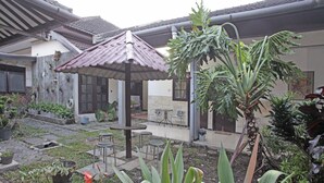 Une cour dotée d’un espace de repos abrité, de plantes en pot et d’un petit jardin.