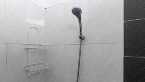 A shower with a handheld showerhead and a wall-mounted faucet, a metal shelf, and a tiled wall with a corner tile pattern. - RedDoorz @ Jagakarsa 2 (Jakarta)