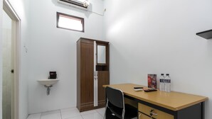 A small, clean room with a wooden desk, a chair, a sink, and a wardrobe. - RedDoorz @ Jagakarsa 2 (Jakarta)
