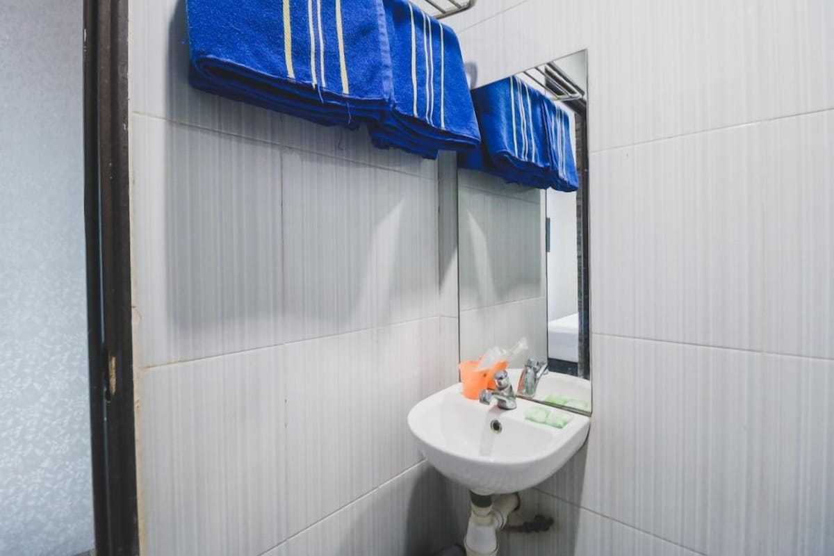 A bathroom with a white sink, a mirror, and blue towels hanging above the sink.
