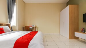 Ein Hotelzimmer mit Bett, Schreibtisch, Stuhl, Kleiderschrank und Fernseher.