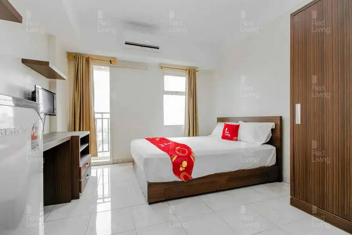 Une chambre d’hôtel avec un lit, une télévision, une armoire et une fenêtre avec des rideaux.