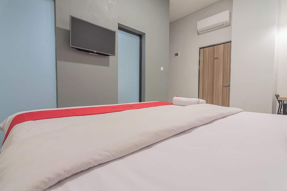Ein Hotelzimmer mit Bett, Wandfernseher, Kleiderschrank und Klimaanlage.