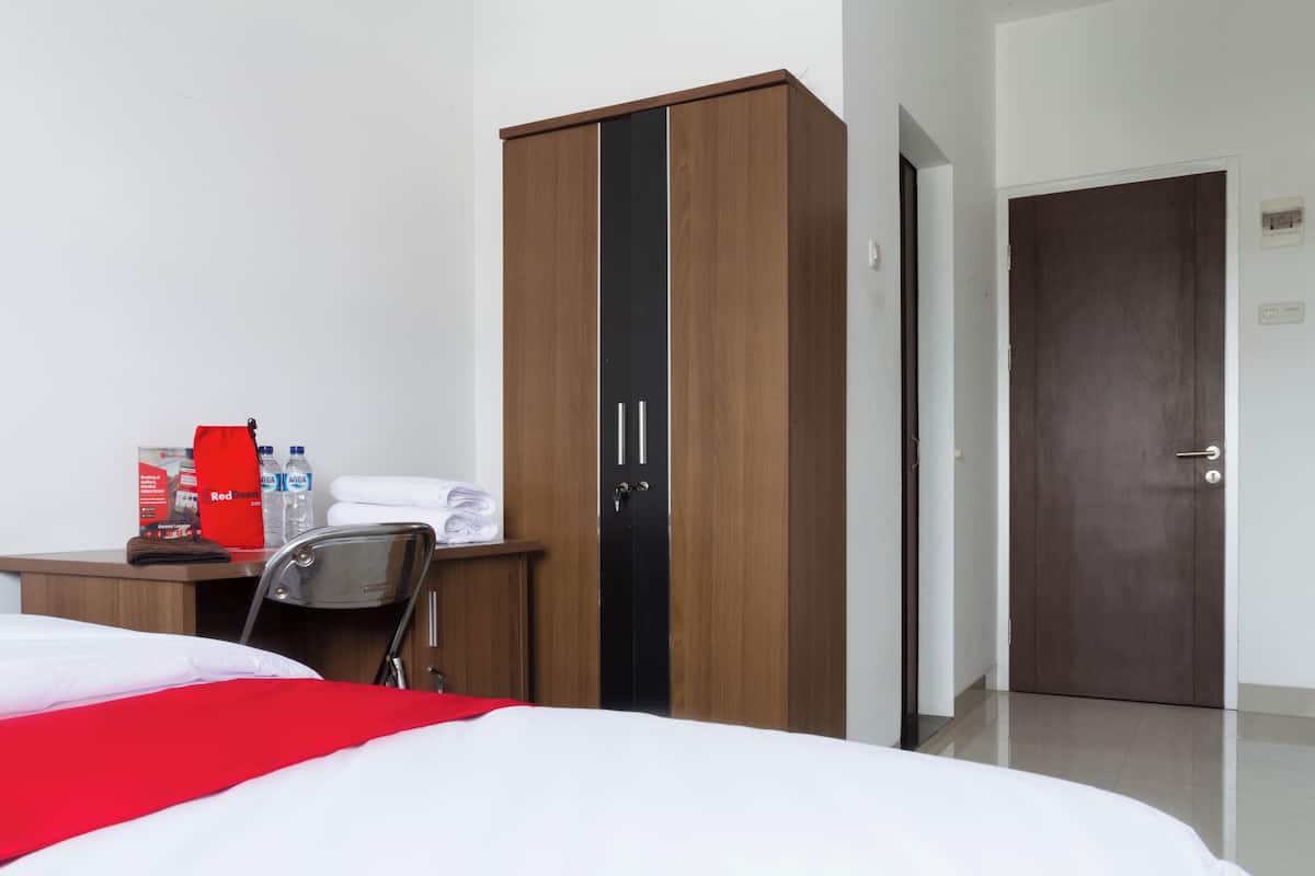 Ein Hotelzimmer mit einem Bett, einem Kleiderschrank, einem Schreibtisch mit Stuhl und einer Tür.