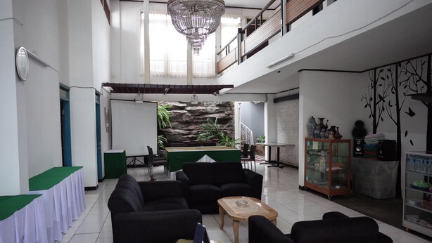 A spacious lobby with a high ceiling, a chandelier, a billiards table, and a seating area with sofas and a coffee table. - RedDoorz near Alun-alun Kota Sukabumi (Sukabumi)