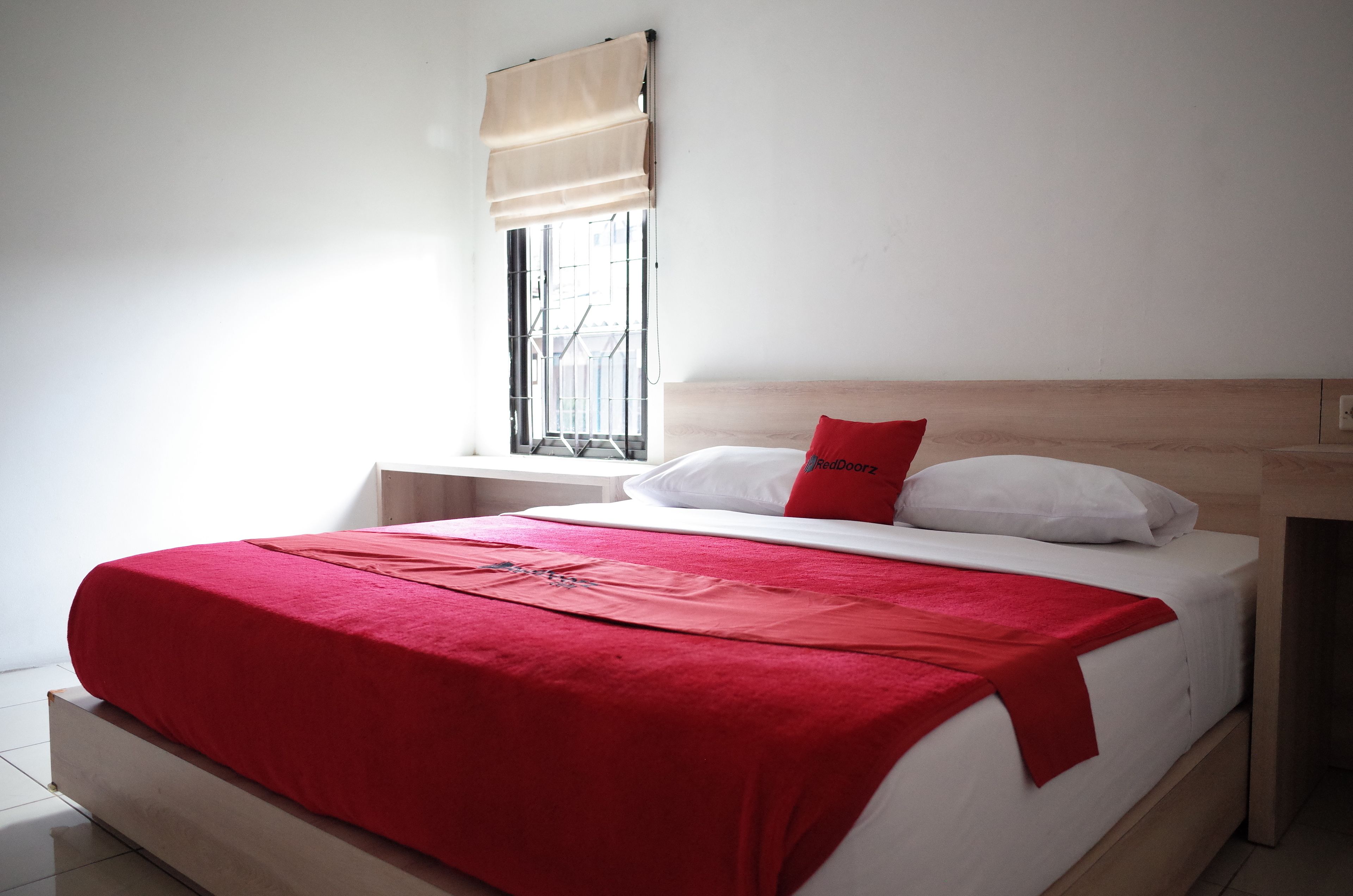A bed with a red blanket, white pillows, and a wooden headboard.