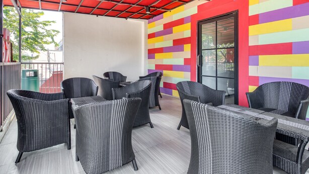 A covered outdoor seating area with wicker furniture and a colorful wall.