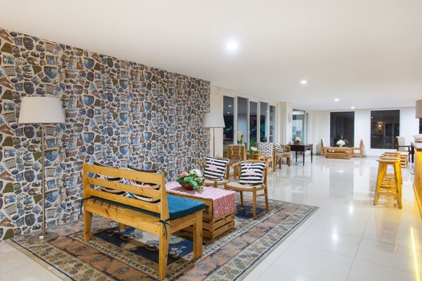 A spacious dining area with a stone wall, wooden furniture, and a view of the outdoors. - RedDoorz Plus @ Riverside Malang (Malang)