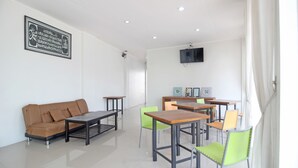 Un salon moderne avec un canapé marron, une table basse, un téléviseur fixé au mur et un coin repas comprenant des chaises et une table.
