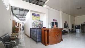 A reception area with a wooden desk, metal chairs, and a sign indicating guest house services. - RedDoorz near Kartini Mall 2 Lampung (Bandar Lampung)