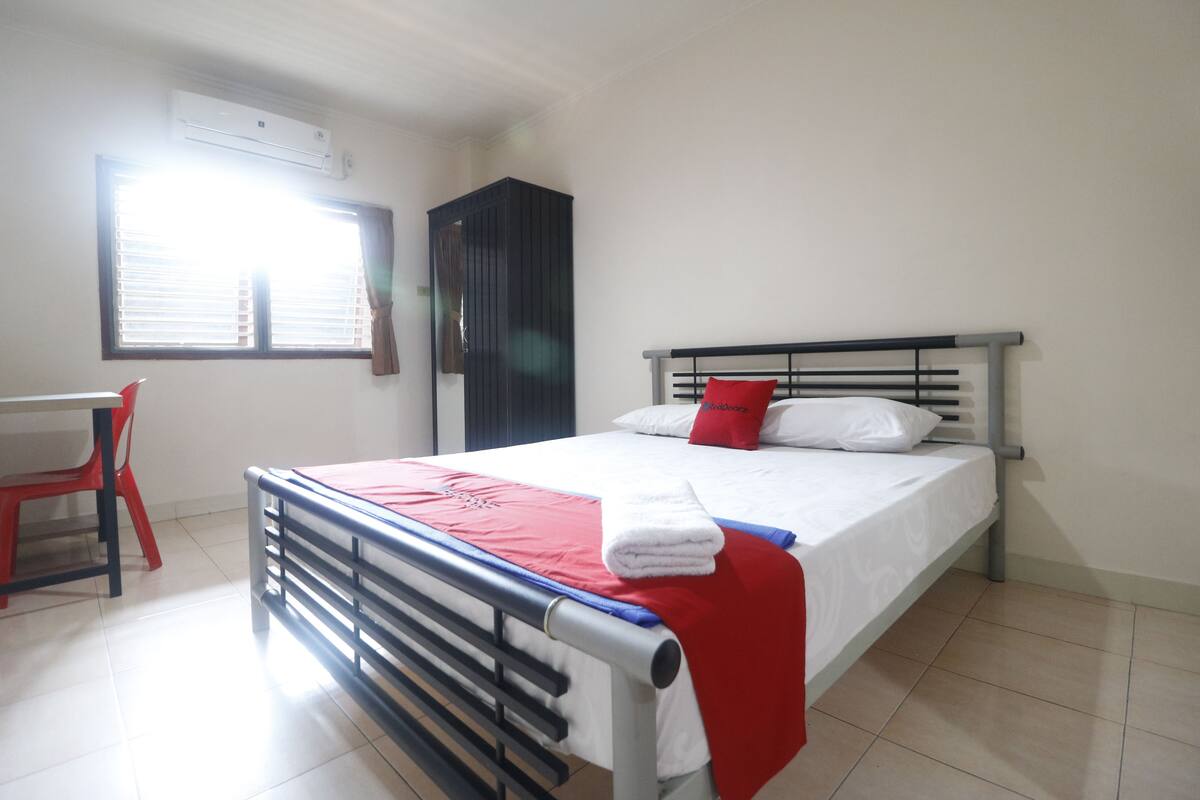 A bedroom with a bed, a desk, and a chair.