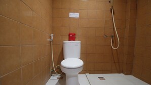 A bathroom with a white toilet, a red tissue box, and a shower. - RedDoorz near Kartini Mall 2 Lampung (Bandar Lampung)