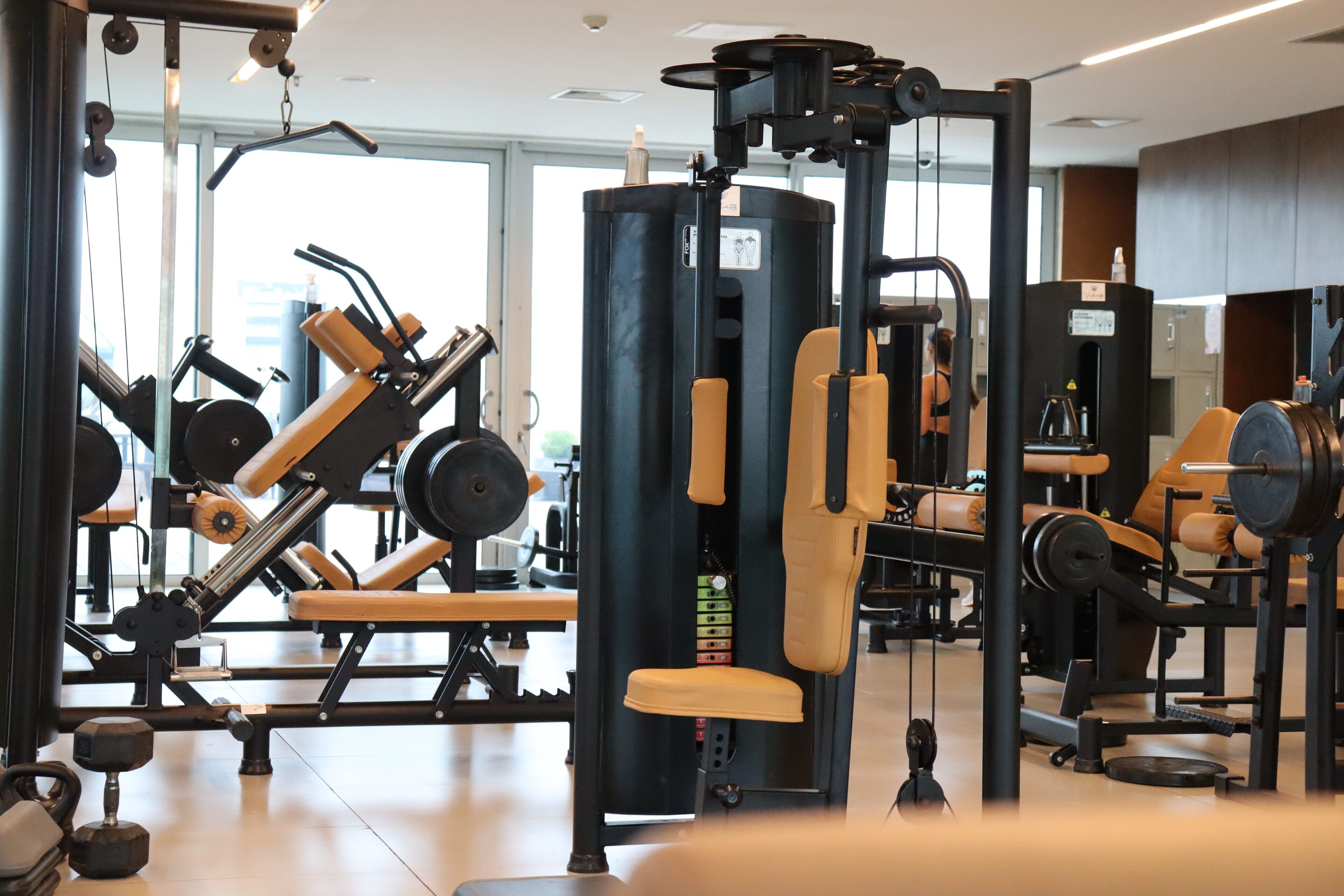 A gym with various exercise machines, weight stacks, and dumbbells.