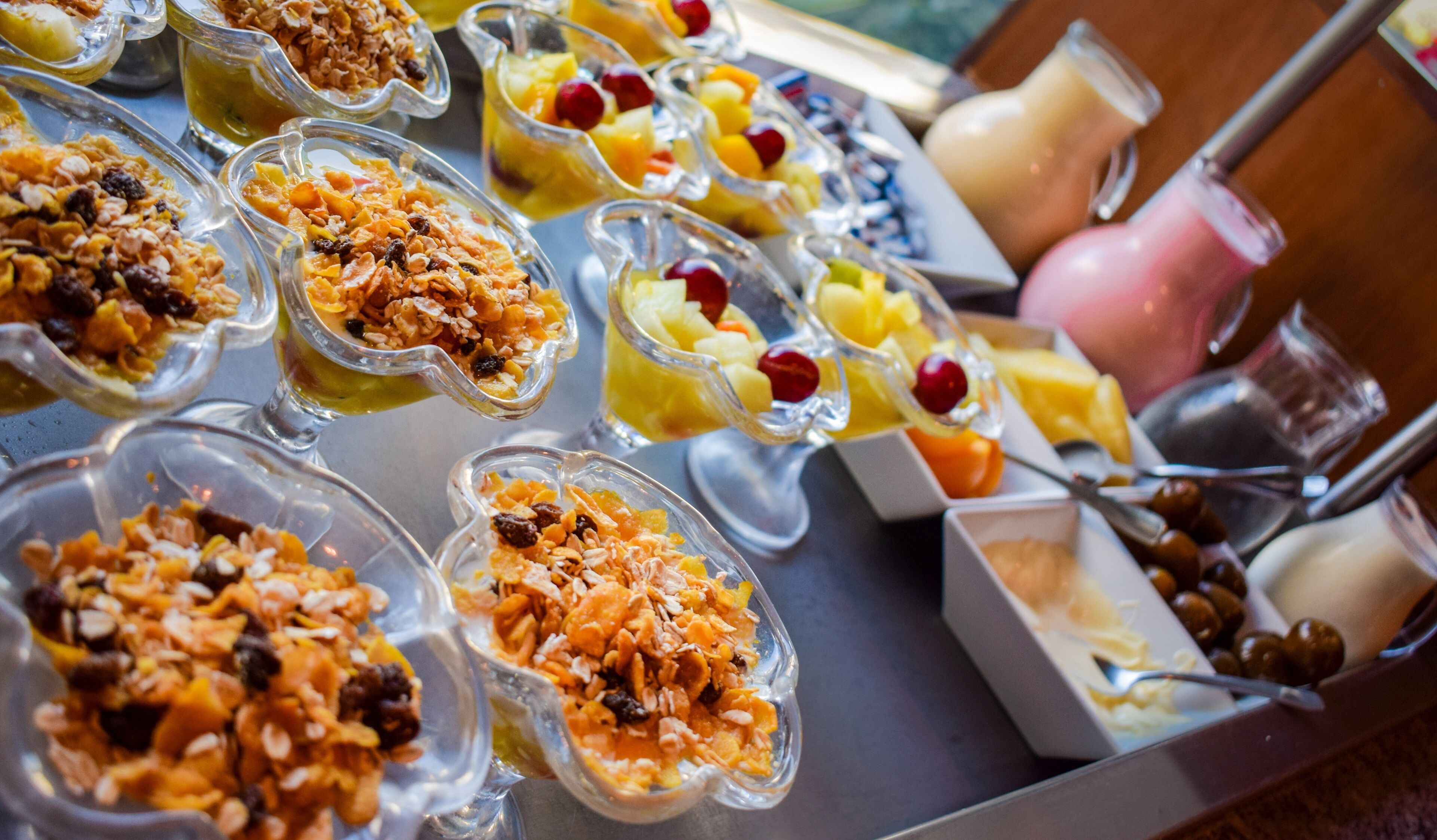 Un bufé con diversas opciones de comida, como frutas, granola y vasos de yogur.
