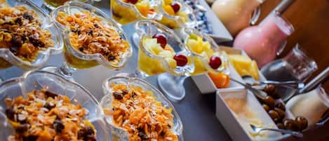 Un bufé con diversas opciones de comida, como frutas, granola y vasos de yogur.