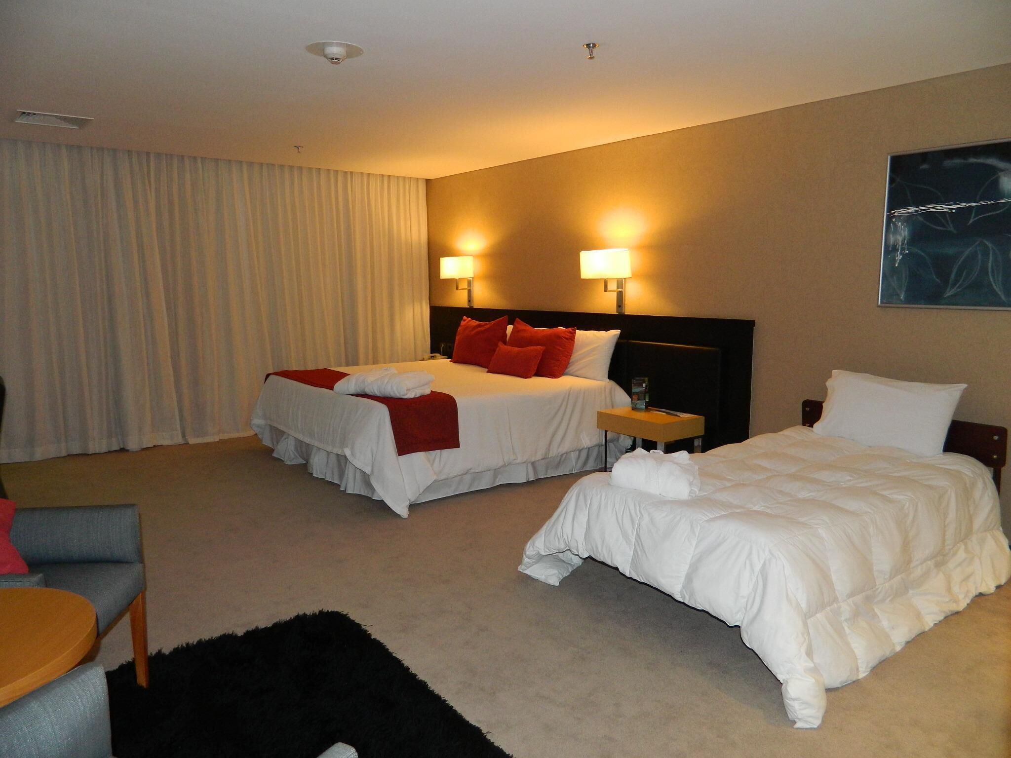 Une chambre d’hôtel avec deux lits, un bureau et une chaise.