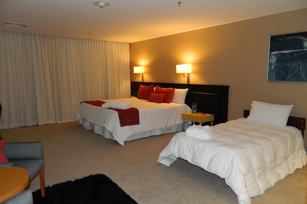 A hotel room with two beds, a desk, and a chair.
