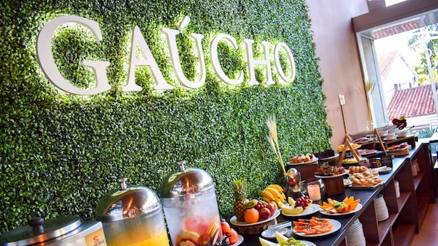 Zona de buffet con una pared verde y un letrero que dice 'GAUCHO'.