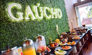 Uma área de buffet com parede verde e um letreiro que diz 'GAUCHO'.