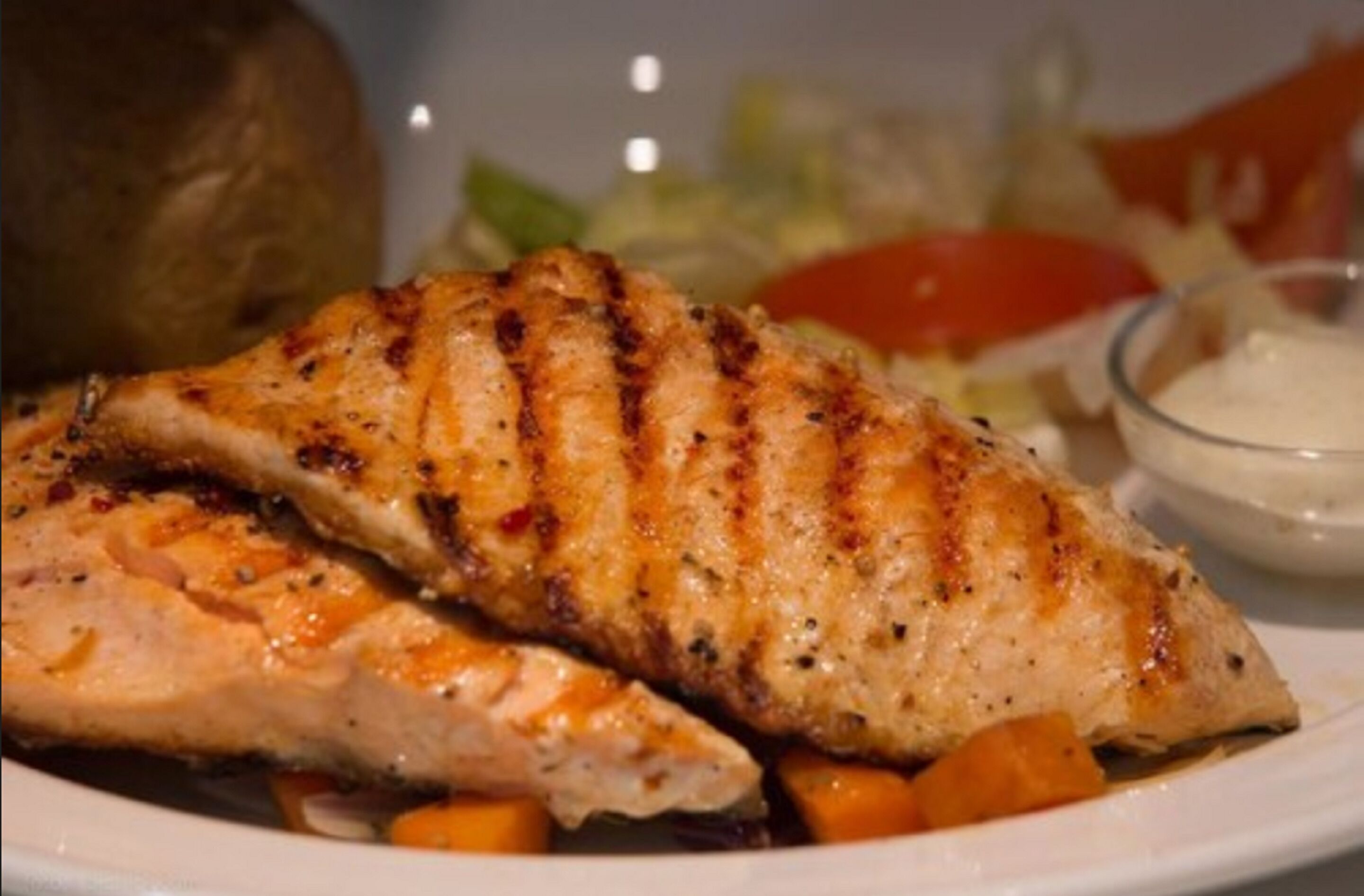Peixe grelhado com legumes num prato.