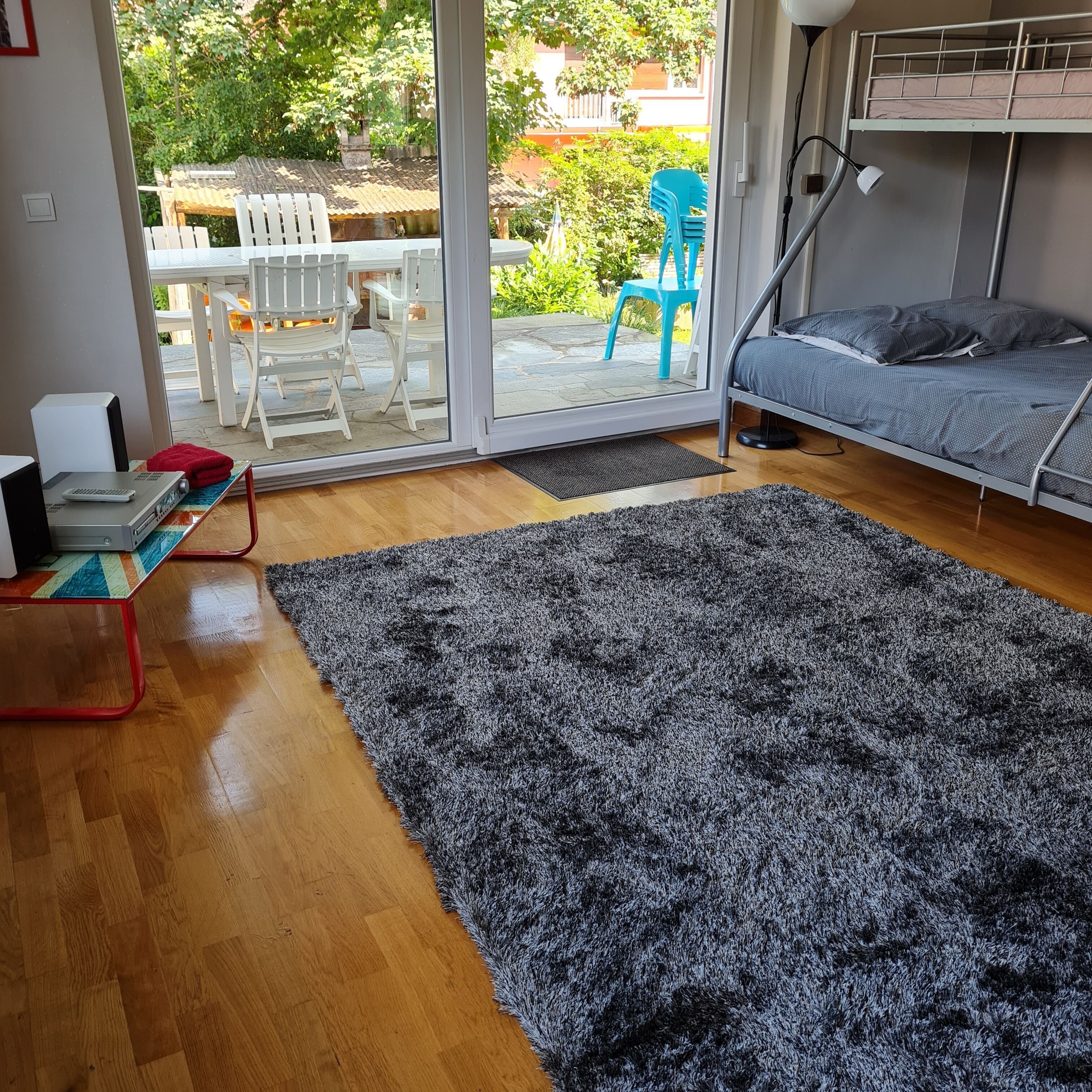 Una habitación con cama, escritorio con ordenador portátil, alfombra y vistas al exterior.