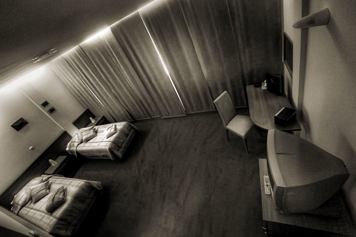 A modern hotel room with a bed, a desk, and a chair.