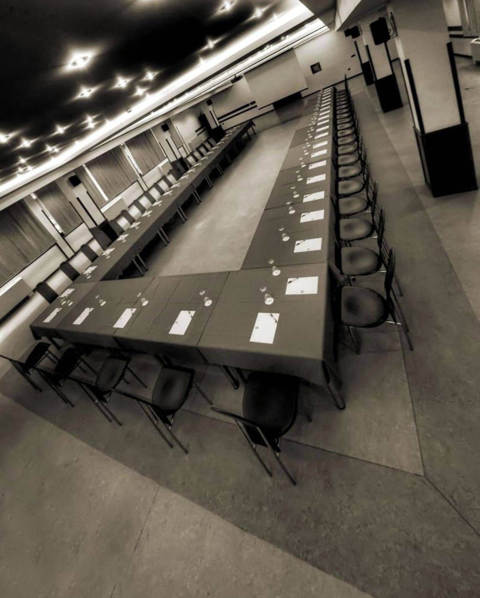 A long conference table with chairs, papers, and a projector screen in a room with a high ceiling and modern design.