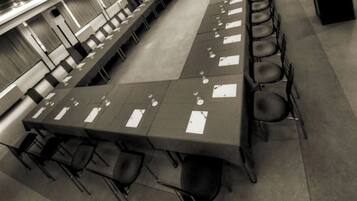 A long conference table with chairs, papers, and a projector screen in a room with a high ceiling and modern design.