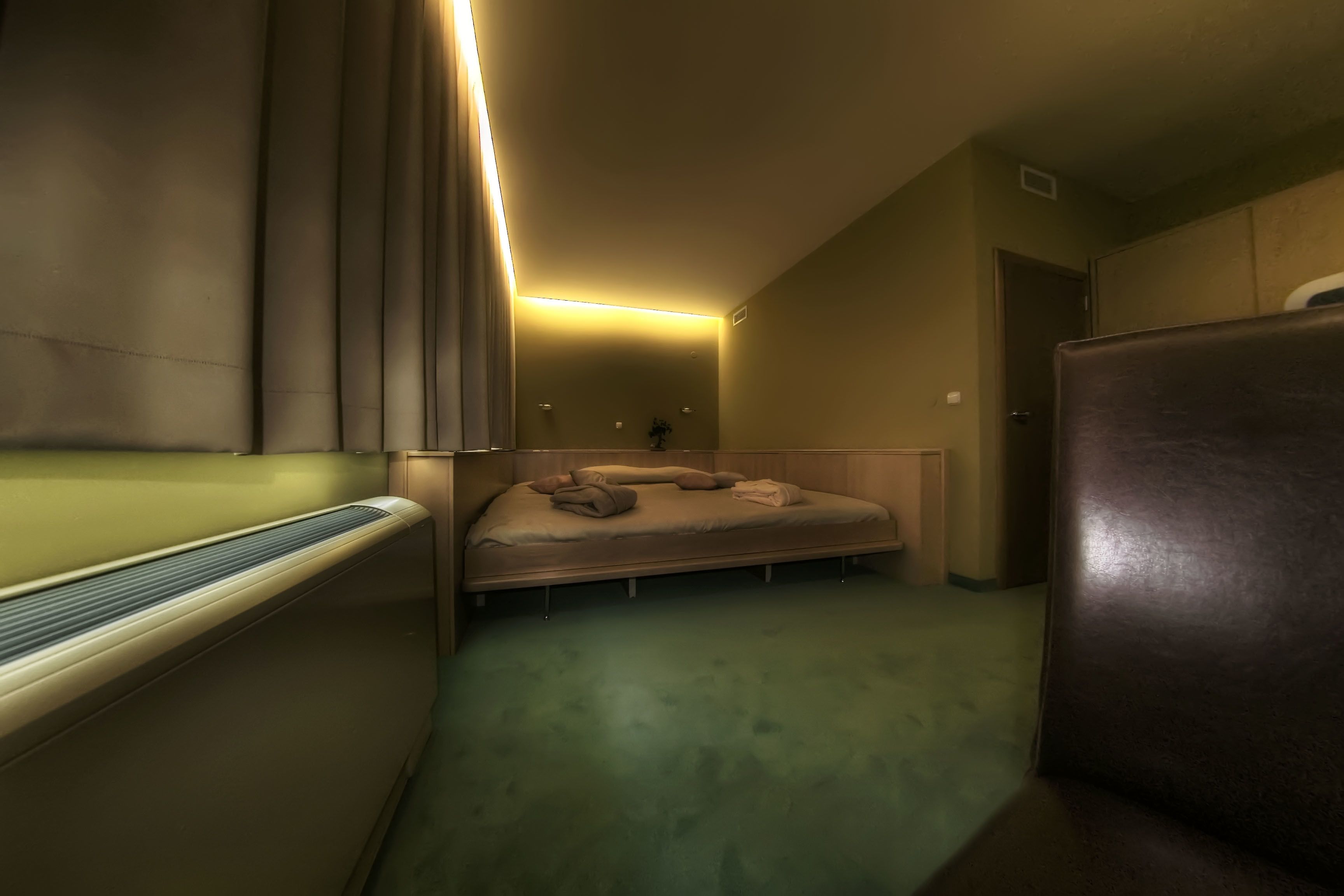 A compact hotel room with a bed, a small seating area, and a bathroom.