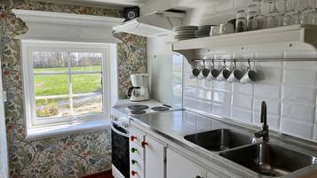 Una cocina con ventana, cafetera, pileta y un mueble con pomos de colores.