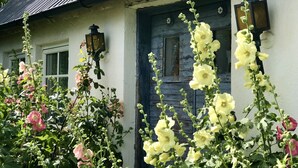 A house with a blue door, a window, and a wall-mounted light fixture. - Sydkustens at Pillehill (Skivarp)