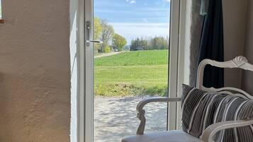 Een gezellige kamer met een witte bank en een bord dat gasten uitnodigt voor het terras.