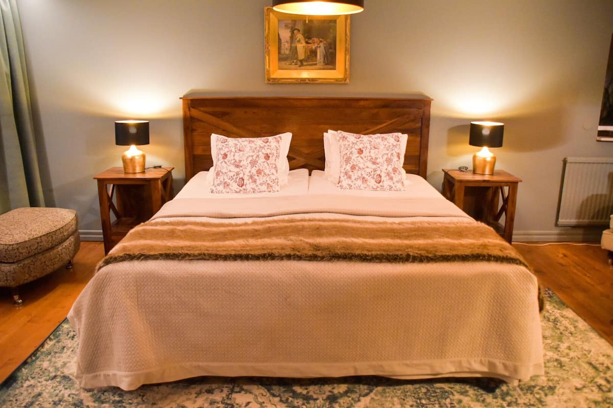 A neatly made bed with a wooden headboard, two bedside lamps, and a framed picture above.