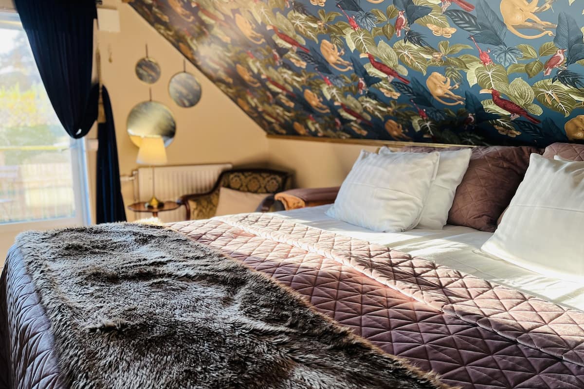 A bedroom with a large bed, a fur throw, and a mural on the wall.