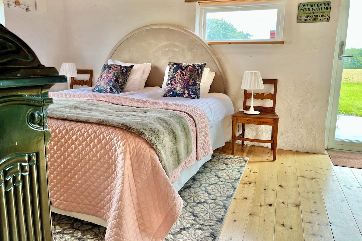A bedroom with a bed, a nightstand, a lamp, a window, and a sign on the wall.