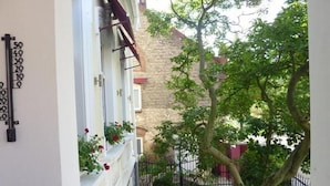 A balcony with a view of a tree and a brick building in the background. - Hotel Berliner Hof Dallgow (Dallgow-Doeberitz)