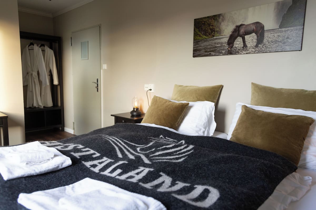 Quarto com cama, almofadas, manta e pintura de um cavalo.