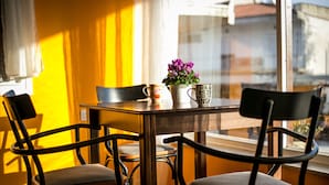 A dining area with a wooden table and four chairs, a potted plant, and two mugs.